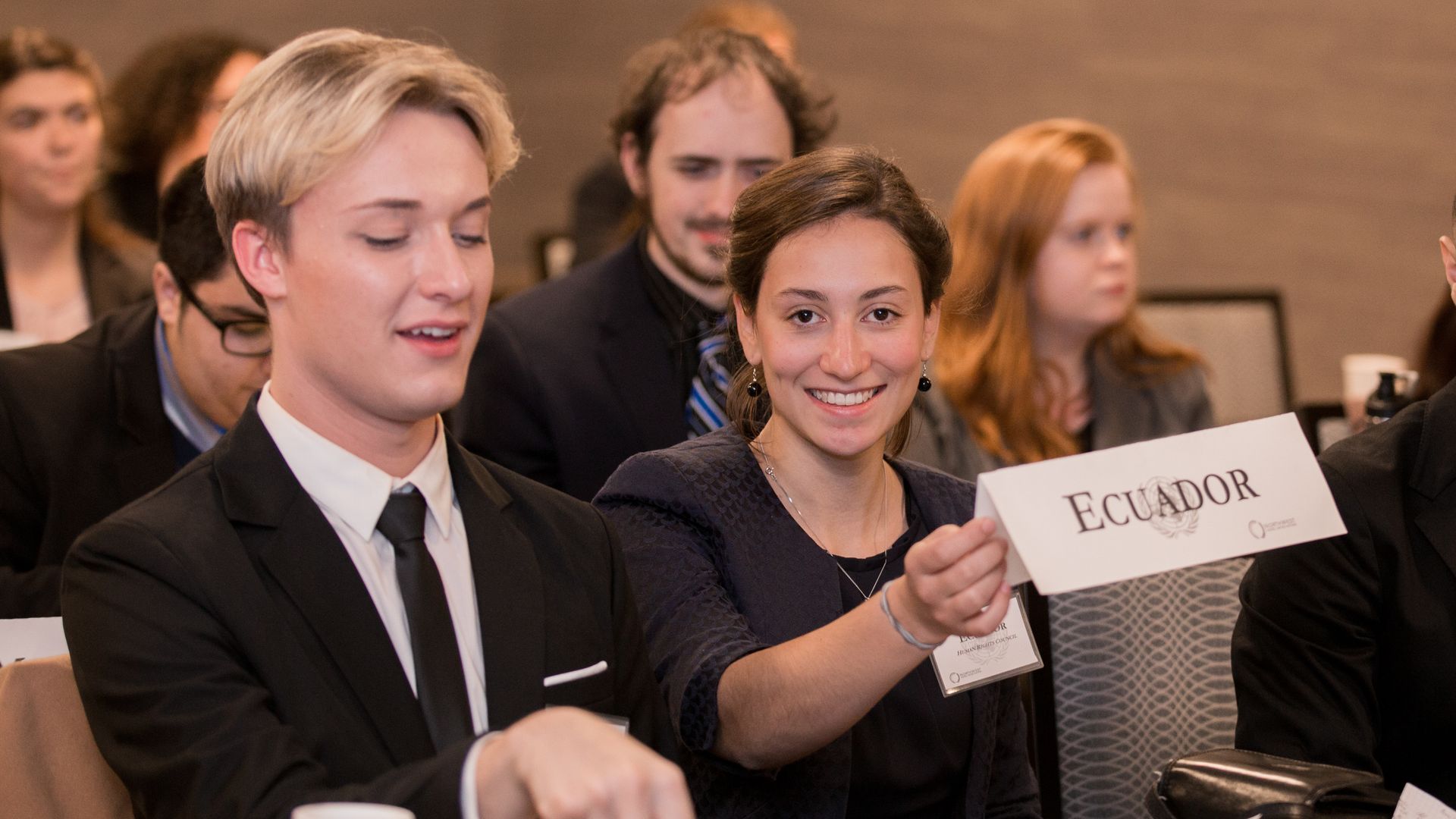 Delegates at a NWMUN conference, including a delegate holding an Ecuador placard